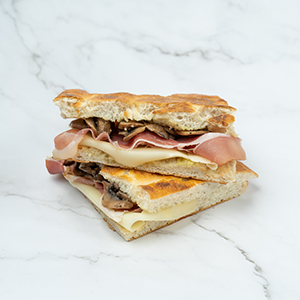 Schiacciata with prosciutto, mushrooms and melted cheese, cut in half